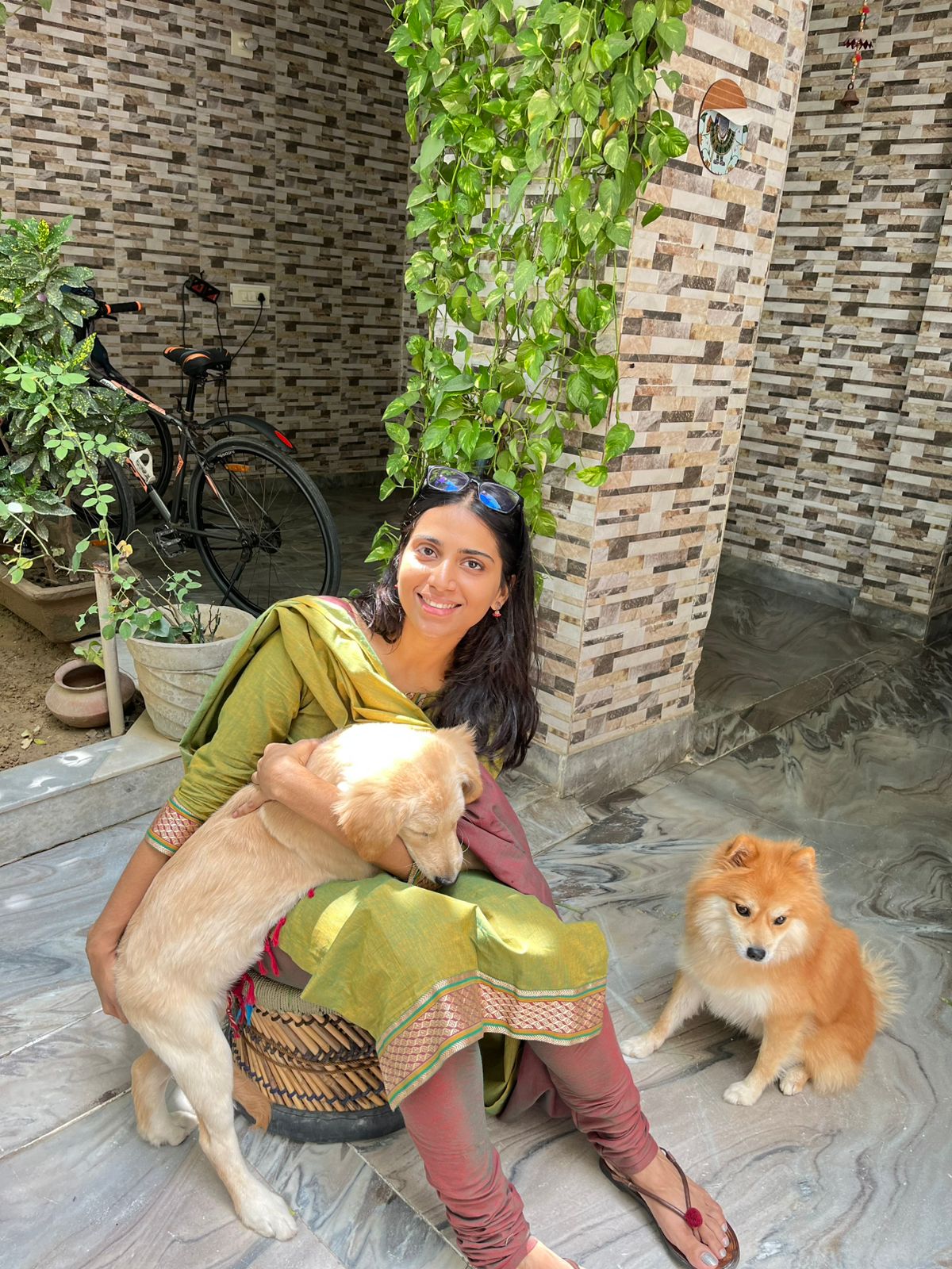 Yukta smiling with her dogs in a sunlit courtyard